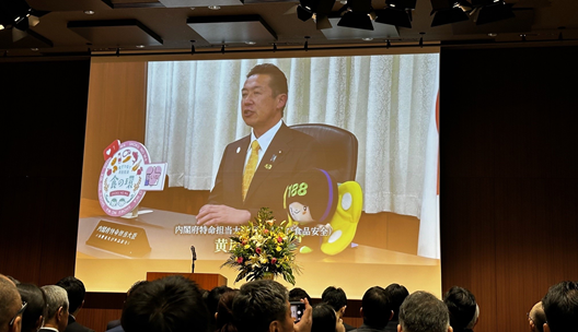 写真:会場のスクリーンに、黄川田大臣のビデオメッセージが流れている