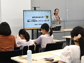 写真:子どもたちが、職員の説明を聞きながらクイズに書き込んでいる様子
