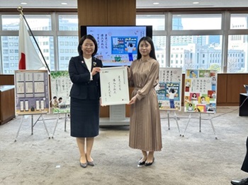 写真:自見大臣と受賞者が、川柳の書かれたパネルを掲げ持っている